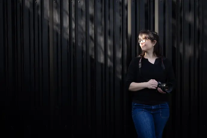 fotograaf tegen een muur met camera in de hand