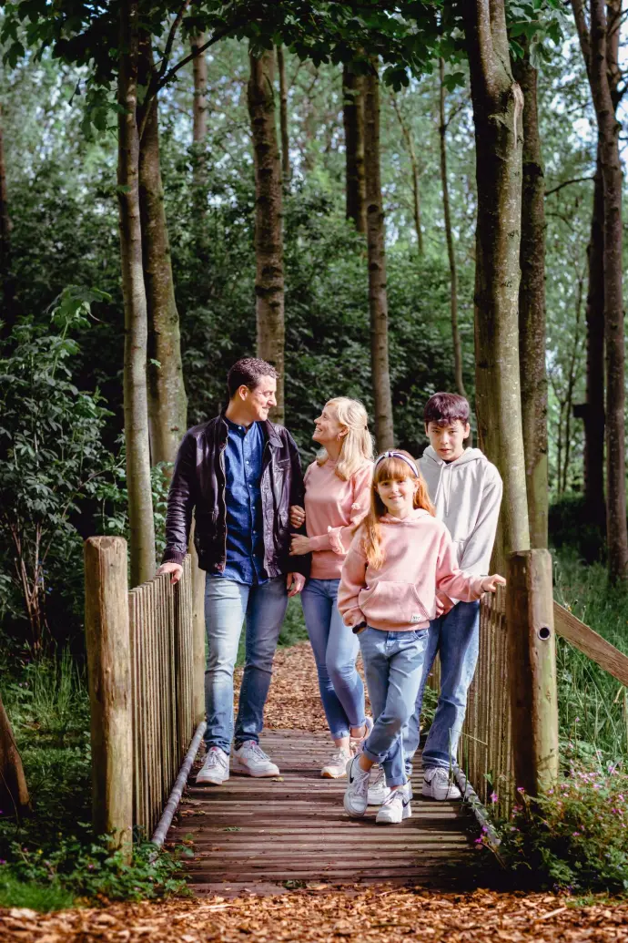 gezin vader moeder zoon en dochter op een brugje in het bos