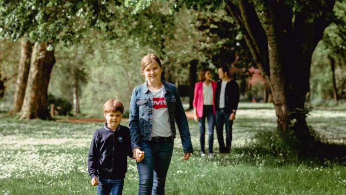 zoon en dochter vooraan in beeld en ouders op achtergrond