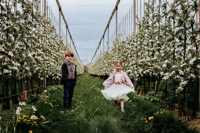 Communie fotosessie met broer en zus in kleurrijke bloesems