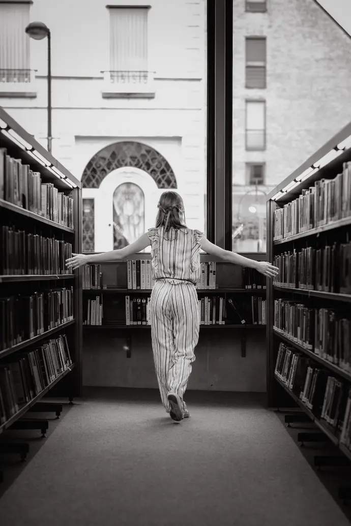 ommunicant poseert tussen boeken in bibliotheek Waregem – stijlvolle communiefoto