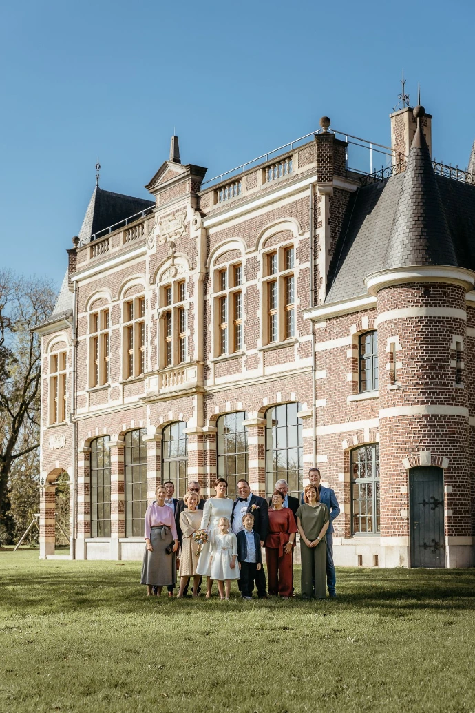 familie en het koppel die is getrouwd in de domein De Ghellinck staan in gras voor het gebouw 