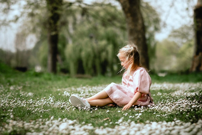 Communiefoto van meisje in pasteljurk tussen bloeiende bloemen