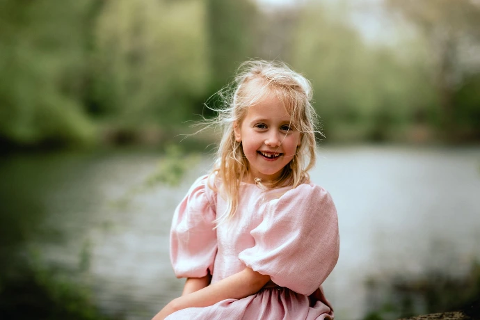 Meisje in communiekleed poseert in idyllische natuur