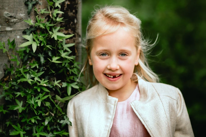 Meisje in communiekleed poseert in idyllische natuur