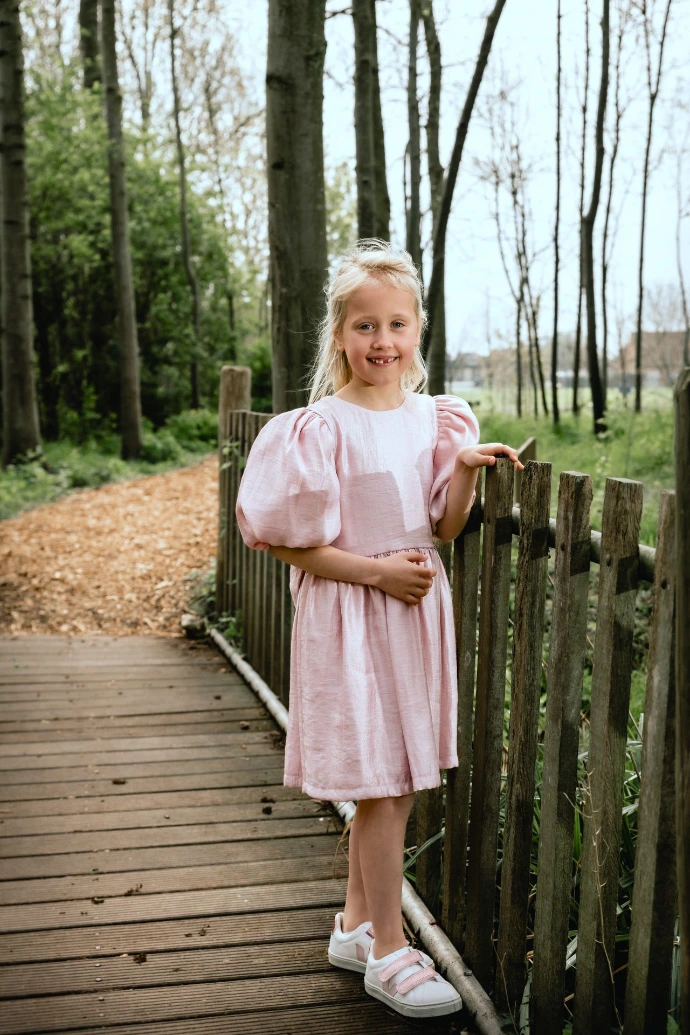 Meisje in communiekleed poseert in idyllische natuur