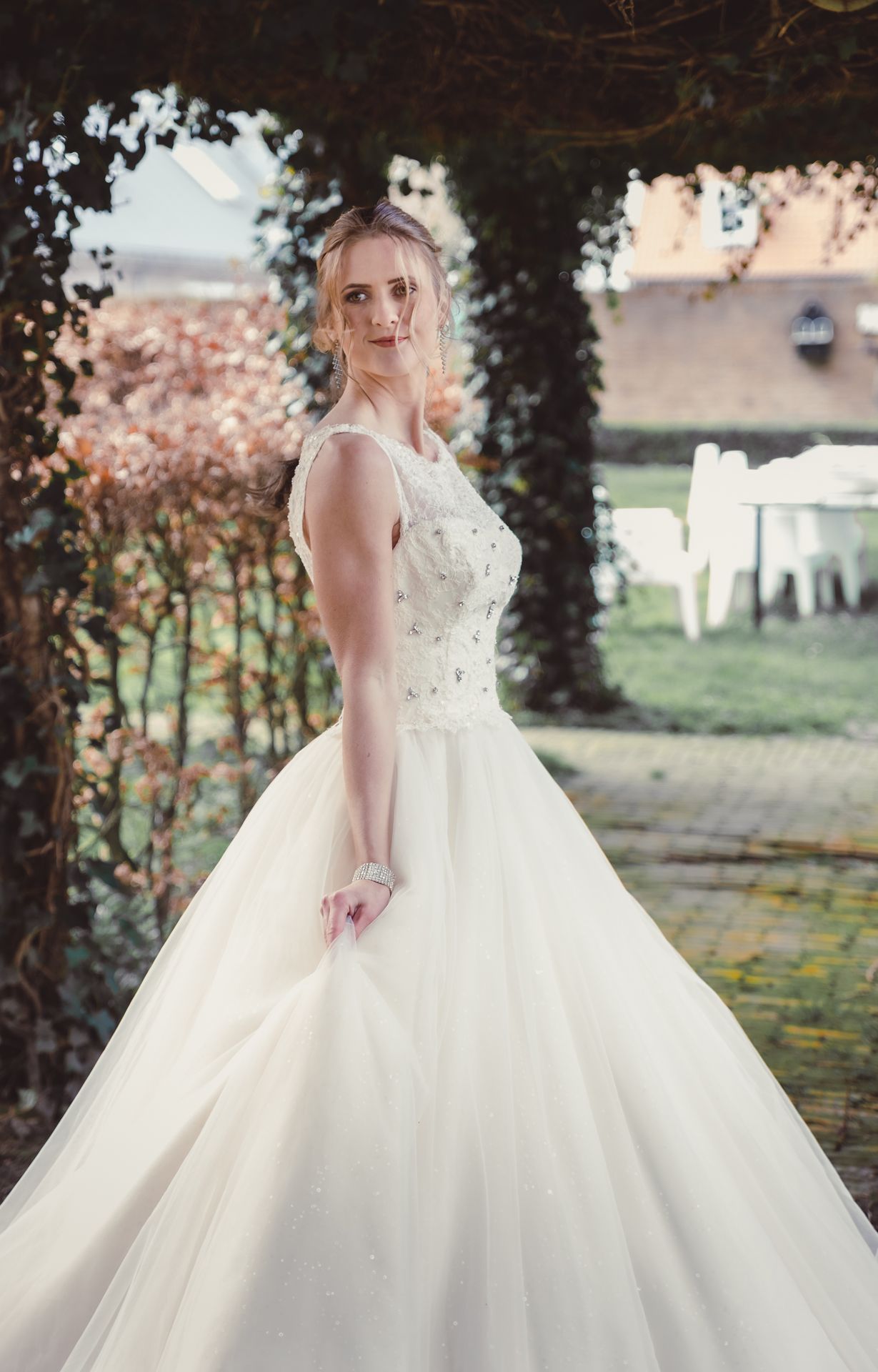 Bruid in sprookjesachtige witte trouwjurk tijdens romantische fotoshoot op landgoed.