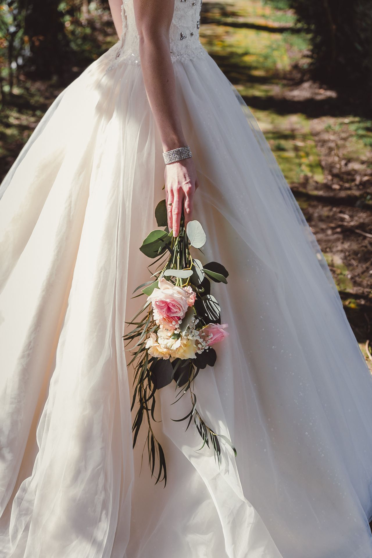 Bruid in sprookjesachtige witte trouwjurk tijdens romantische fotoshoot op landgoed.