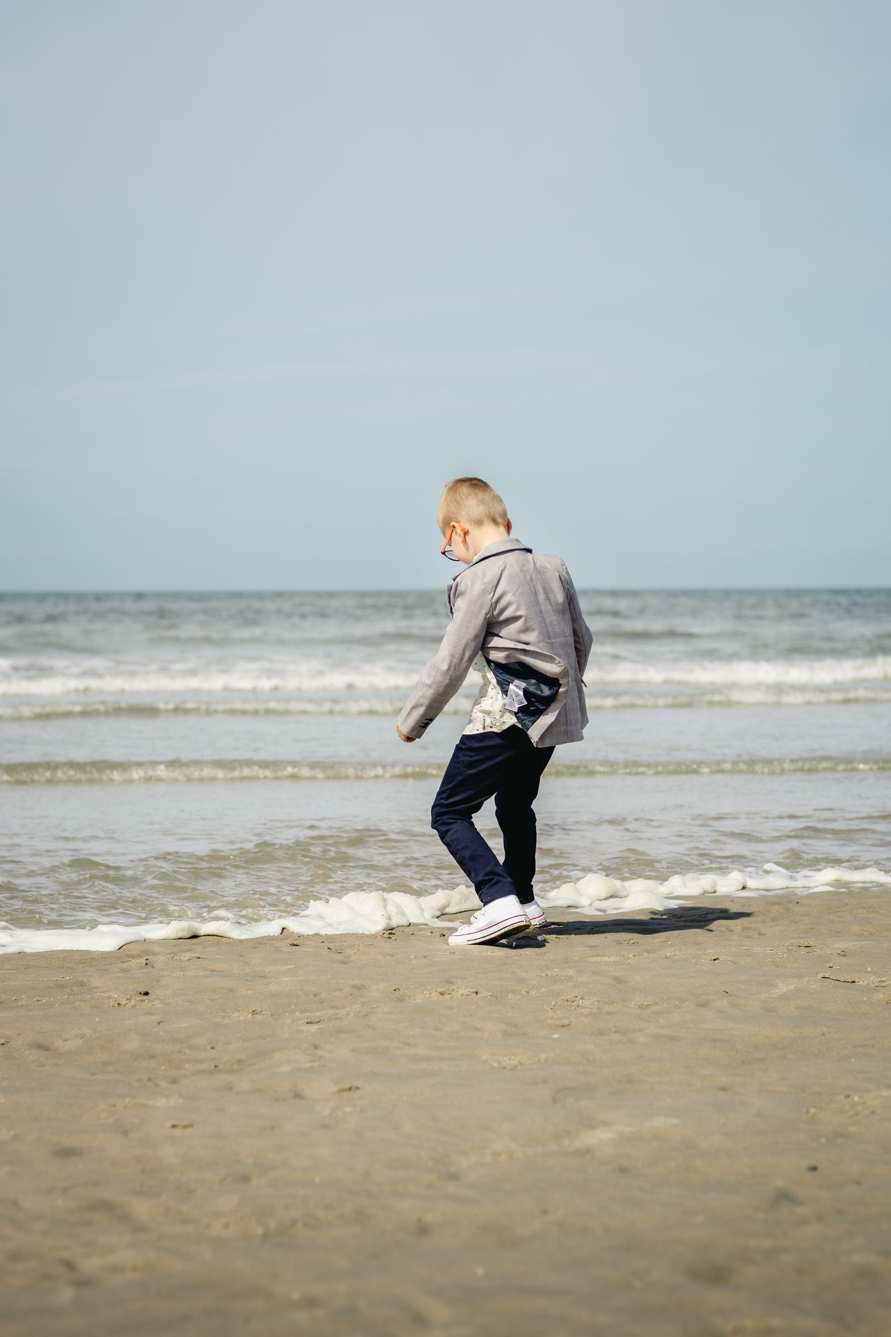 Fotoshoot voor lentefeest aan zee met stijlvolle outfit, duinen en bomen in zonnige setting.