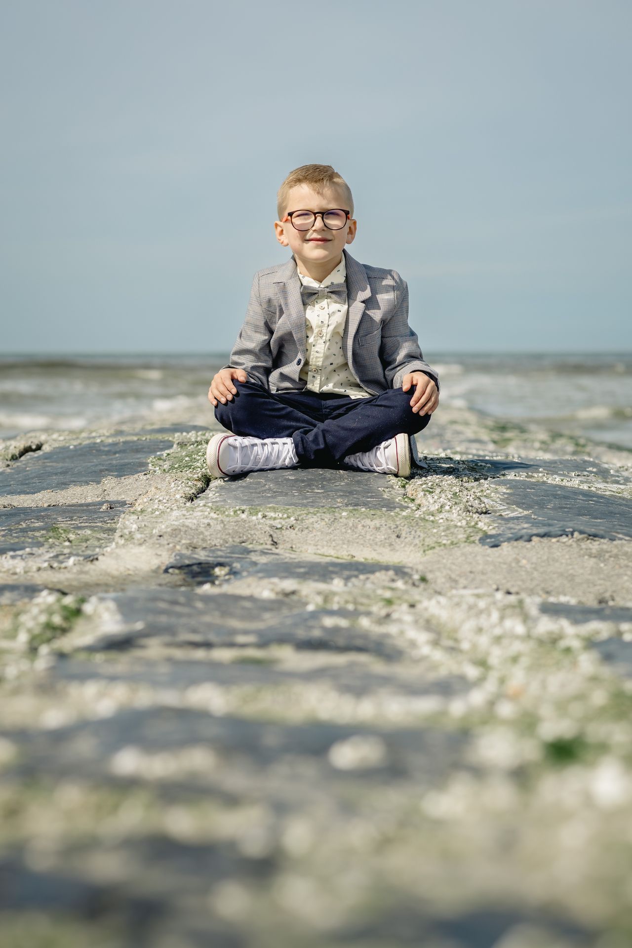 Fotoshoot voor lentefeest aan zee met stijlvolle outfit, duinen en bomen in zonnige setting.
