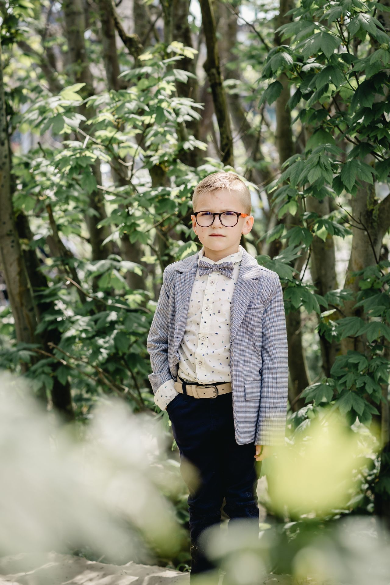 Fotoshoot voor lentefeest aan zee met stijlvolle outfit, duinen en bomen in zonnige setting.