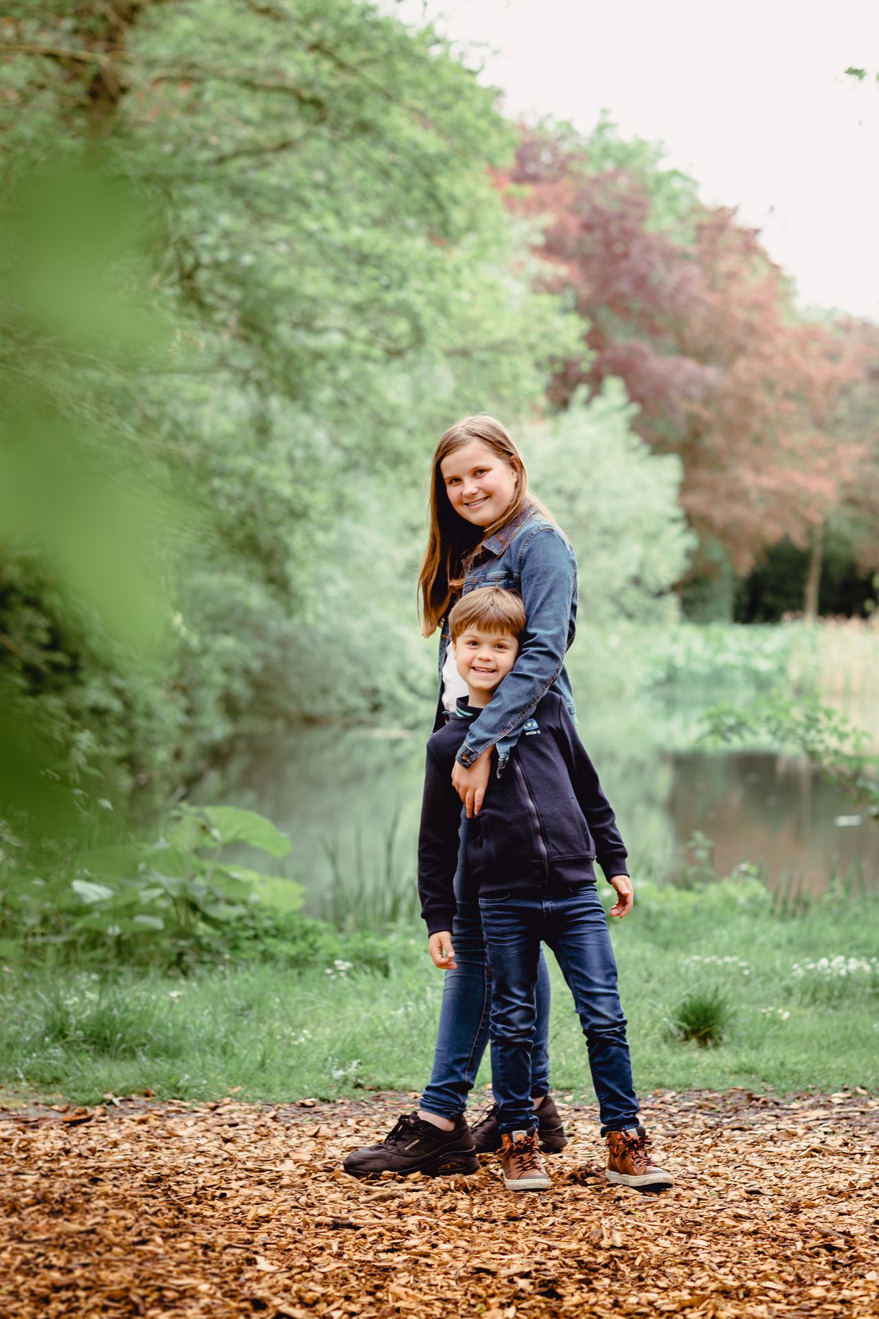 Familiefotoshoot in zonovergoten veld met hoge wolken en warme sfeer.