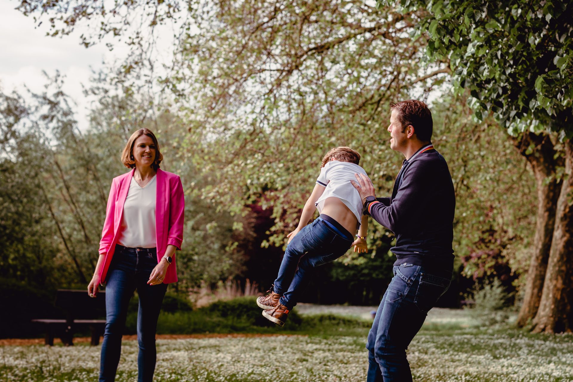 Familiefotoshoot in zonovergoten veld met hoge wolken en warme sfeer.