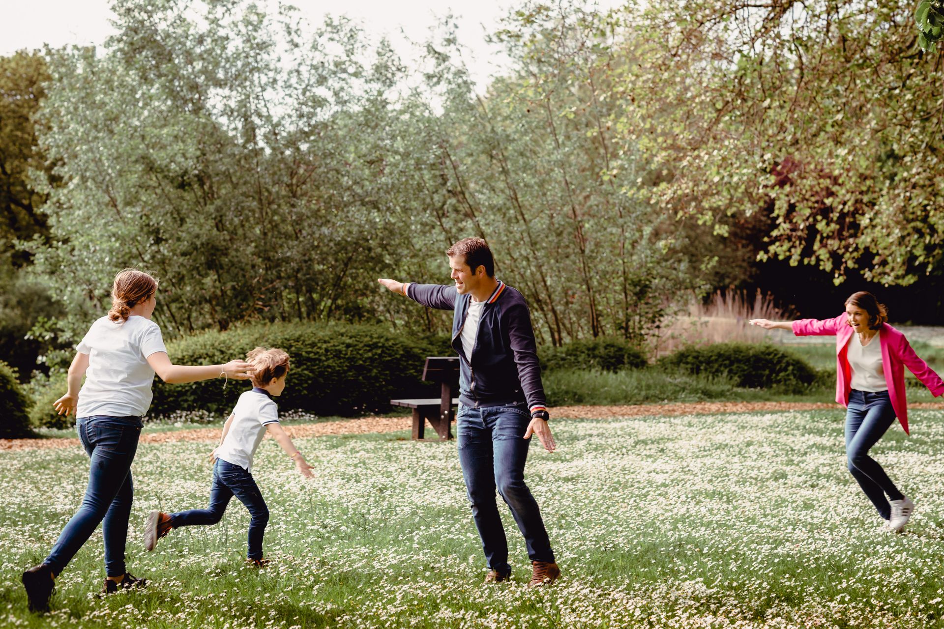 Familiefotoshoot in zonovergoten veld met hoge wolken en warme sfeer.