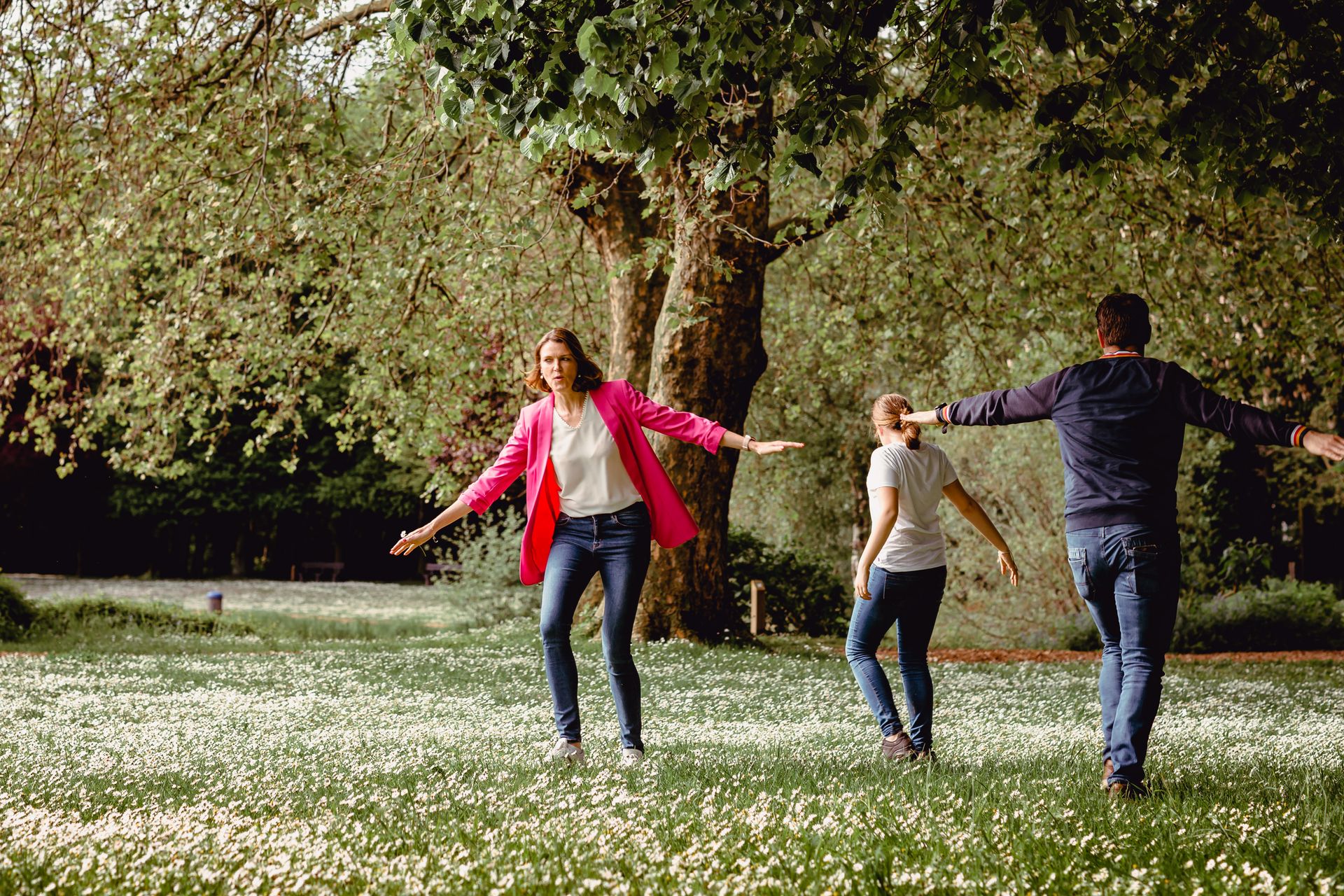 Familiefotoshoot in zonovergoten veld met hoge wolken en warme sfeer.