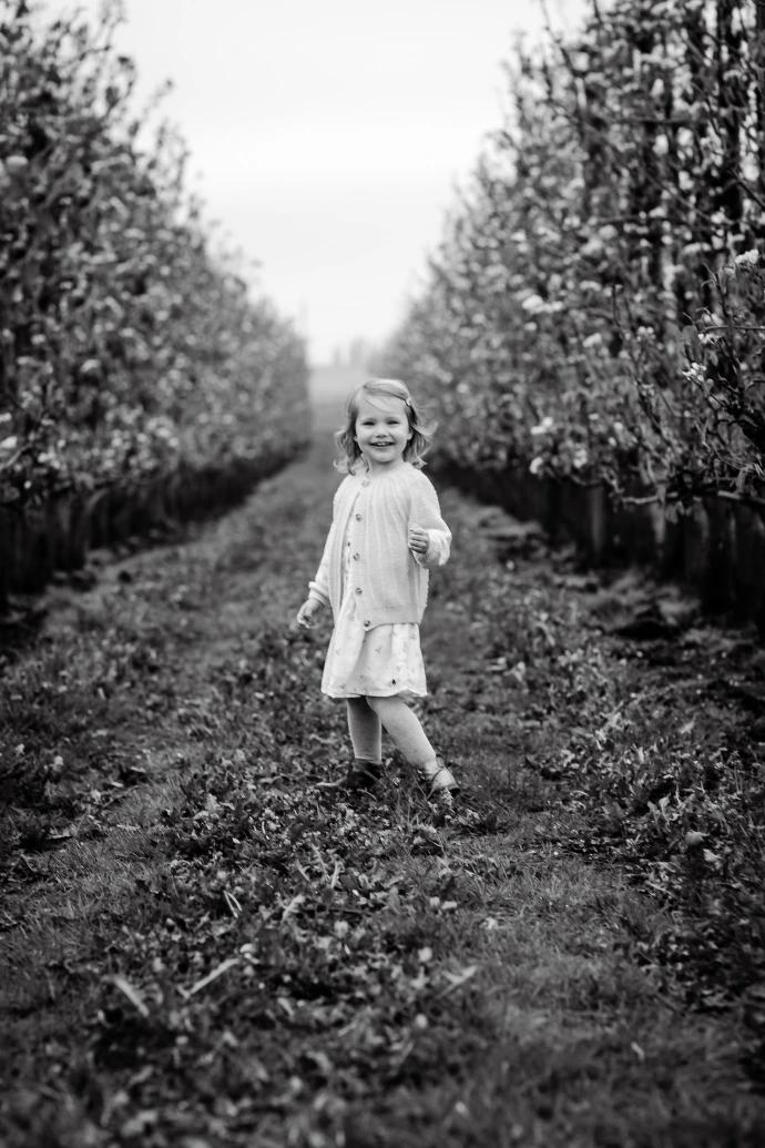 Tijdloze familiefotografie in appelboomgaard met bloesems en lichte regenbuien