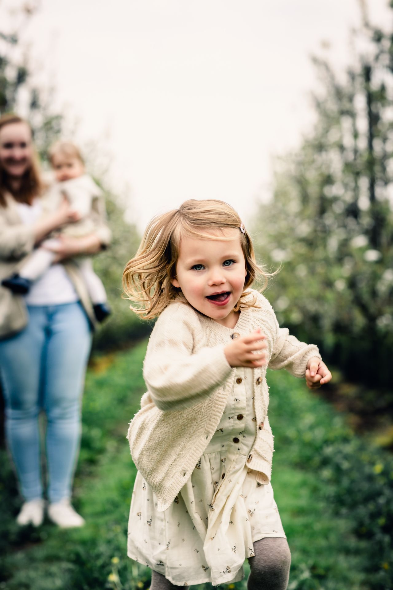 Tijdloze familiefotografie in appelboomgaard met bloesems en lichte regenbuien