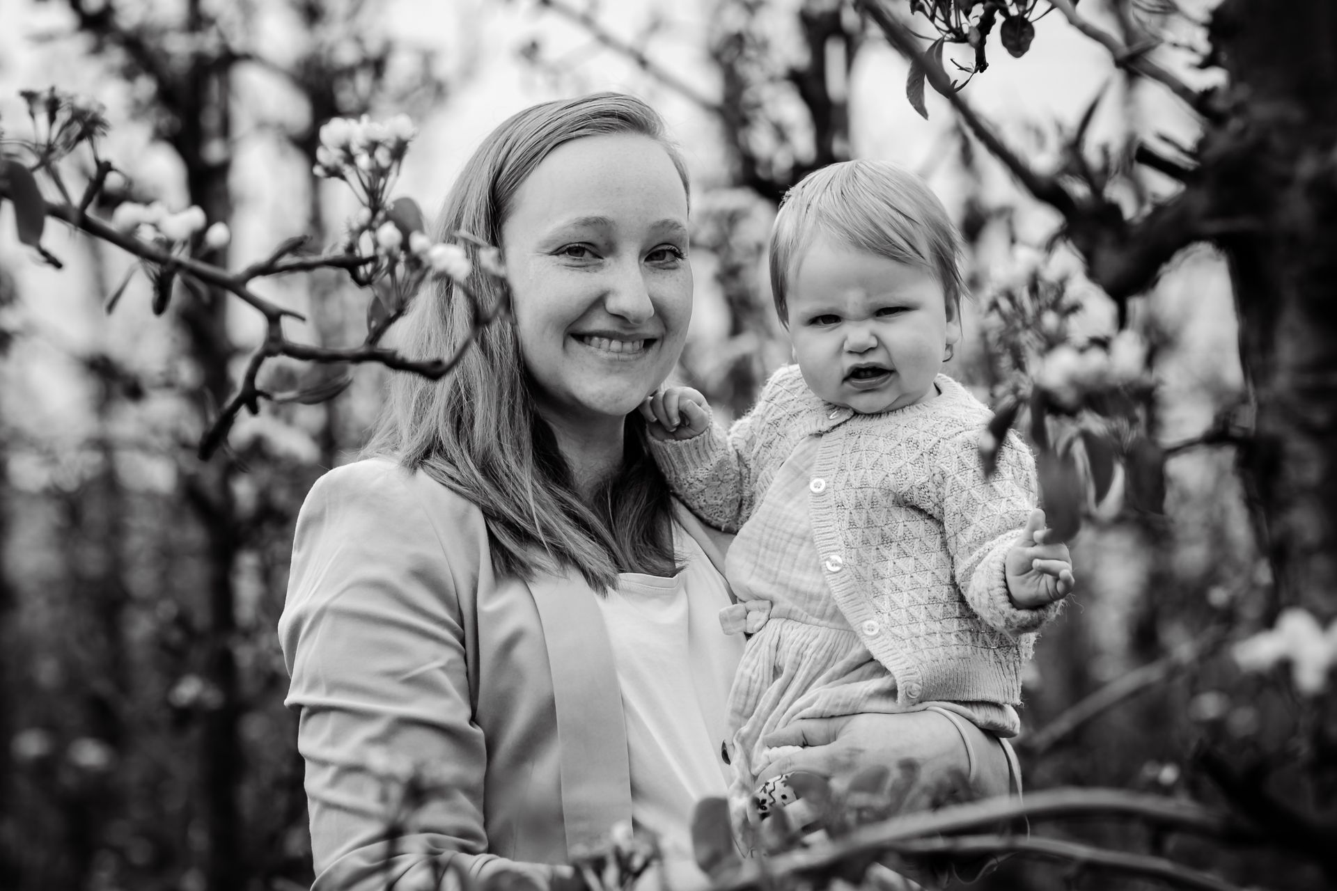Familiefotoshoot in bloeiende appelboomgaard op regenachtige dag in België.