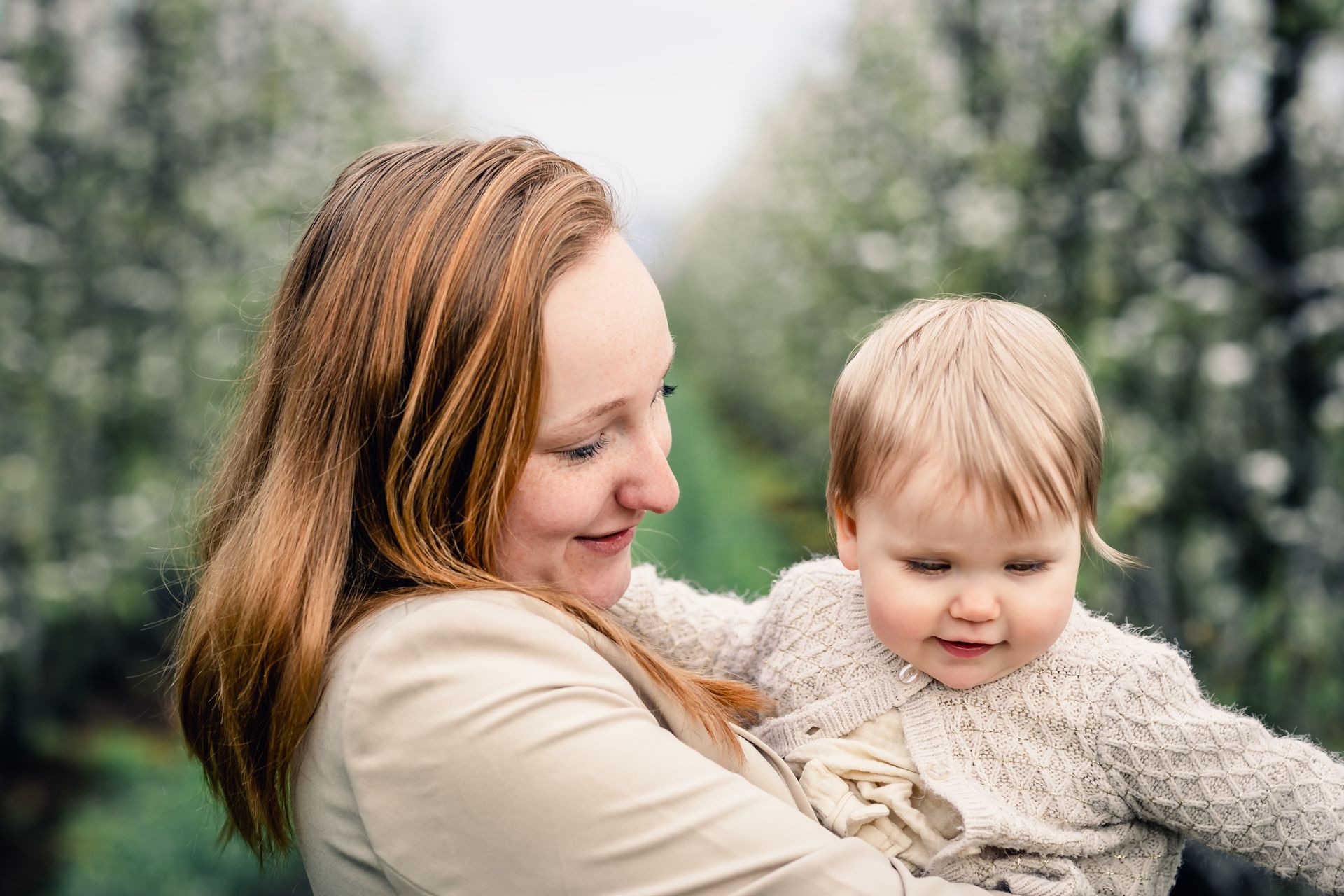Gezinsmomenten vastgelegd tussen appelbloesems met zachte regen voor natuurlijke sfeer.