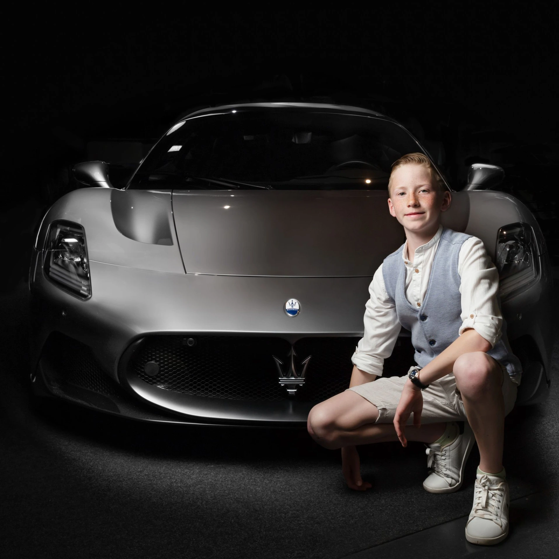 Vooraanzicht van een Maserati MC20 in een donkere studio-opstelling met dramatische belichting.