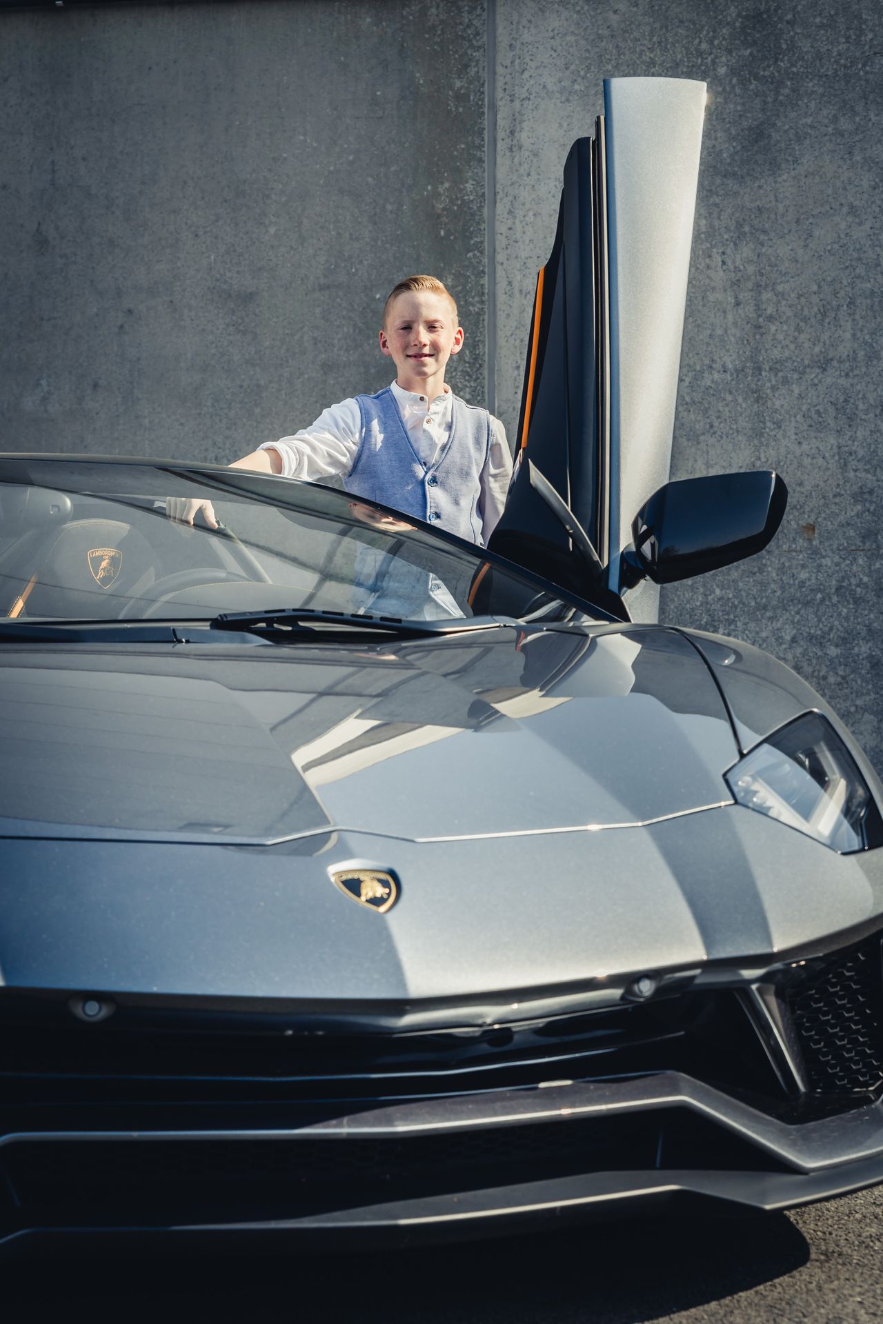 Communieshoot met een zilveren Lamborghini Aventador Roadster met openstaande vleugeldeuren.