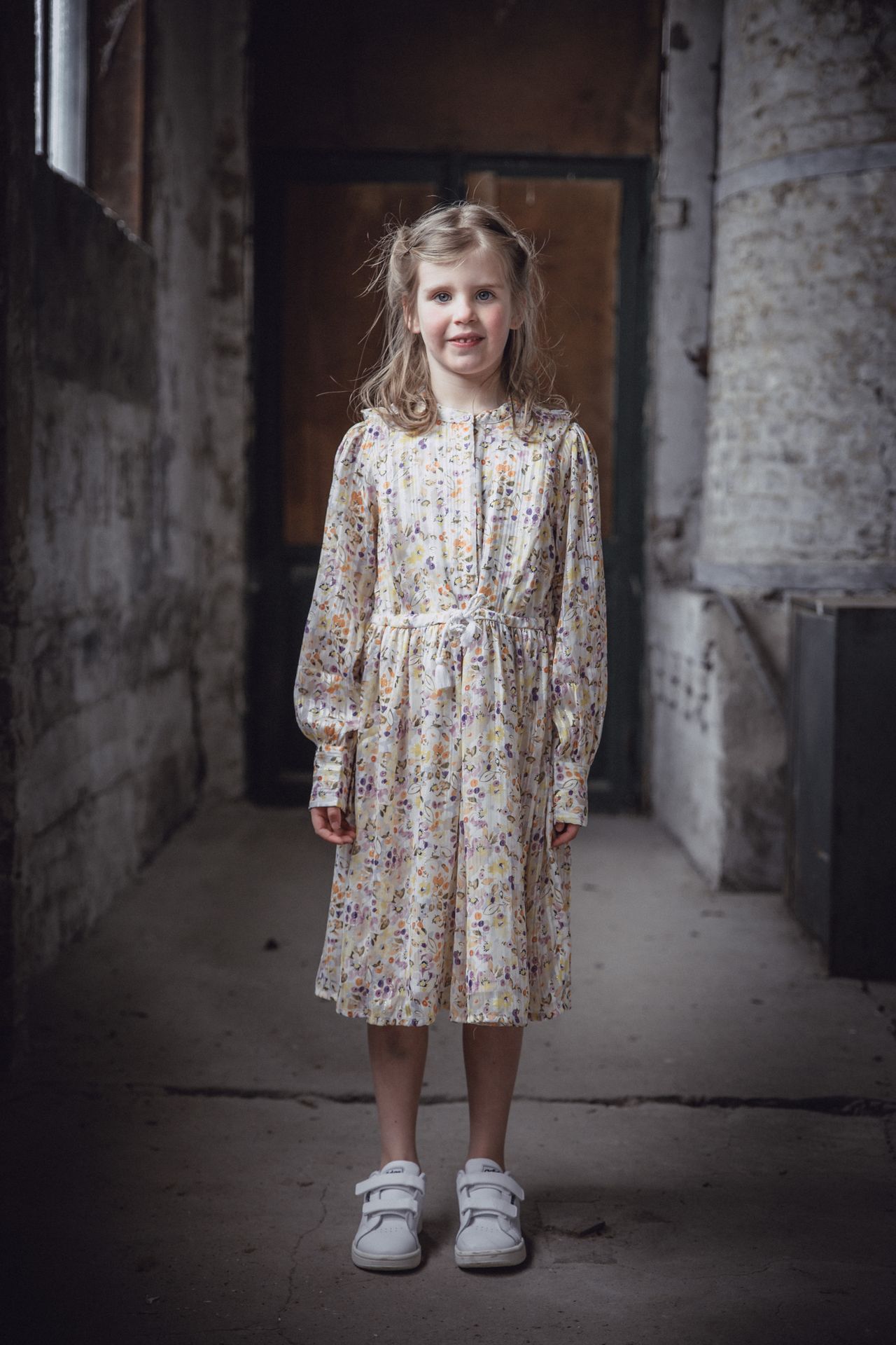 Speels poseerend kind in een lichte, oude fabriekshal.