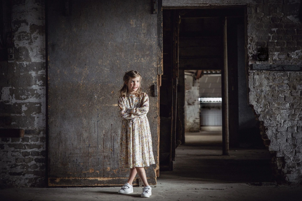 Communiekind in elegante outfit in een oude industriële fabriek
