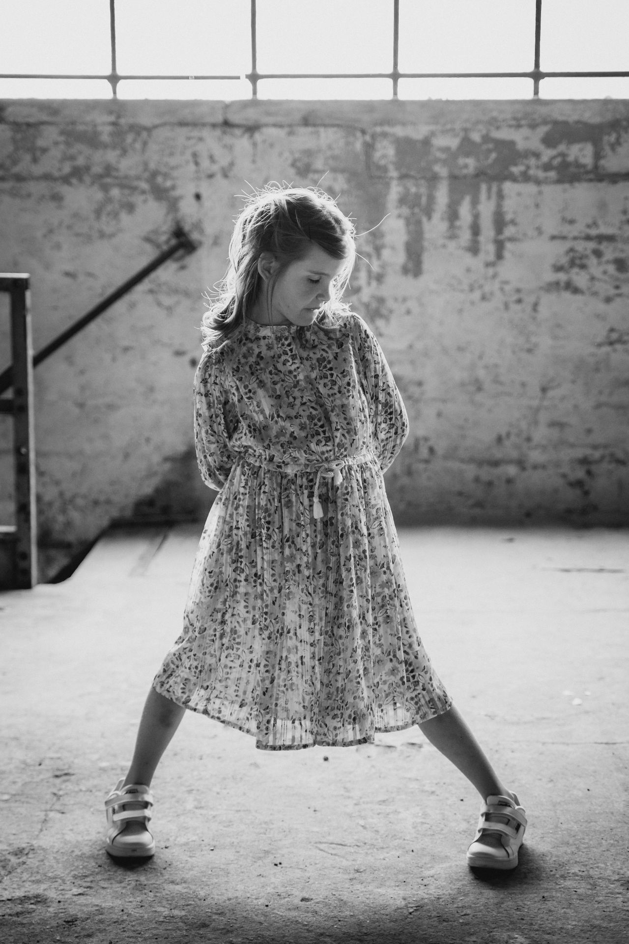 Speels poseerend kind in een lichte, oude fabriekshal.