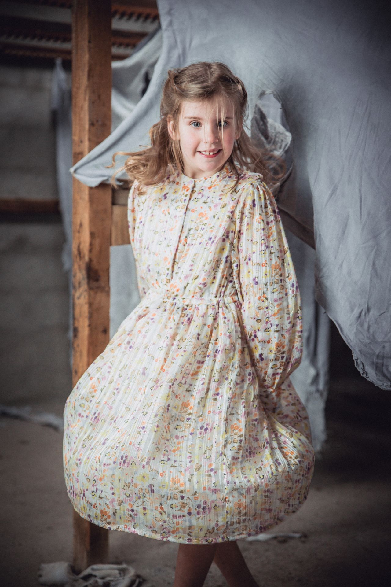 Speels poseerend kind in een lichte, oude fabriekshal.