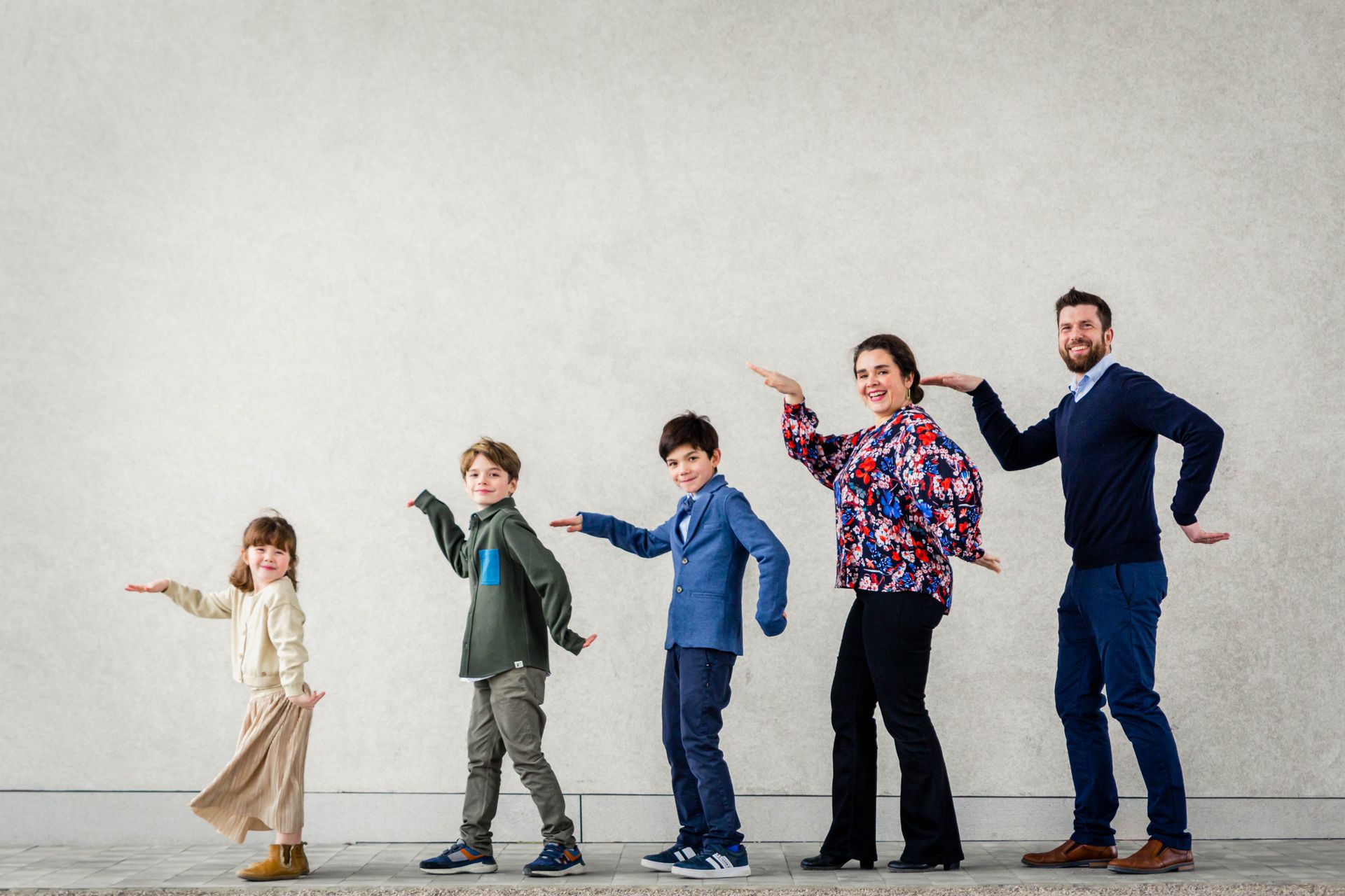 Gezin poseert samen tijdens buitenshoot bij bibliotheek.