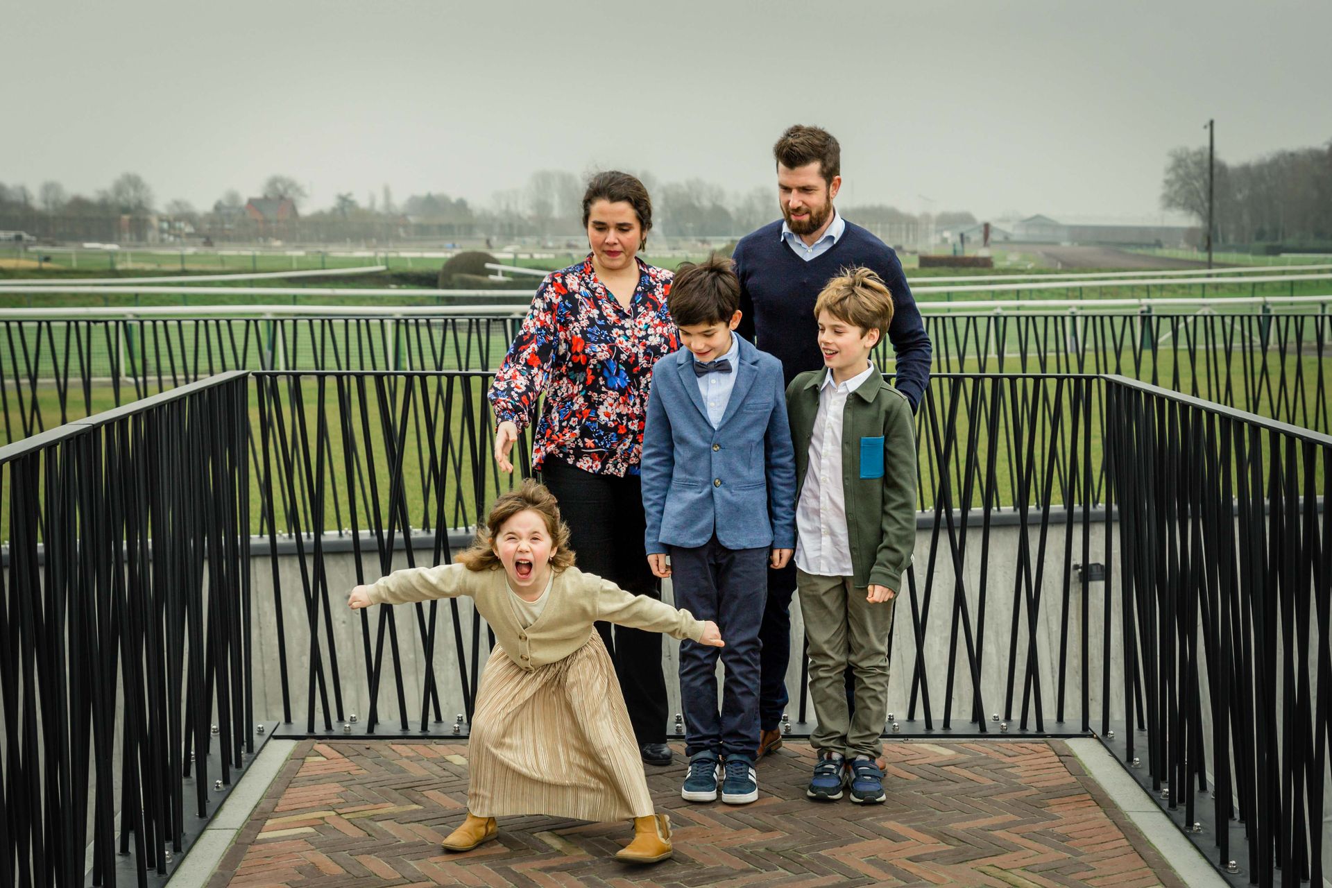 Gezin poseert samen tijdens buitenshoot bij bibliotheek.