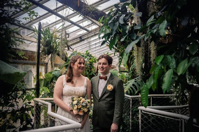 Bruidspaar dat geniet in de regen tijdens hun trouwdag in Plantentuin Meise.