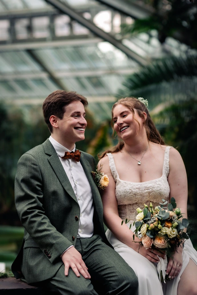 Bruidspaar dat geniet in de regen tijdens hun trouwdag in Plantentuin Meise.