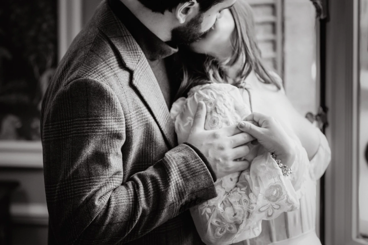 Romantic portrait of a couple by a castle window during their anniversary getaway.